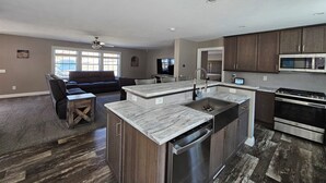 A modern kitchen with dark wood cabinets, a stainless steel dishwasher, and a built-in oven. - Newly built secluded home, large game room, full RV hook-up (Mears)