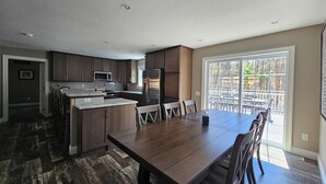 A modern kitchen with dark wood cabinets, a central island, and a dining area with a large table and chairs. - Newly built secluded home, large game room, full RV hook-up (Mears)