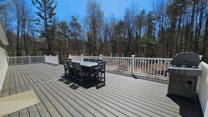 A wooden deck with a dining table and chairs, a grill, and a white railing. - Newly built secluded home, large game room, full RV hook-up (Mears)