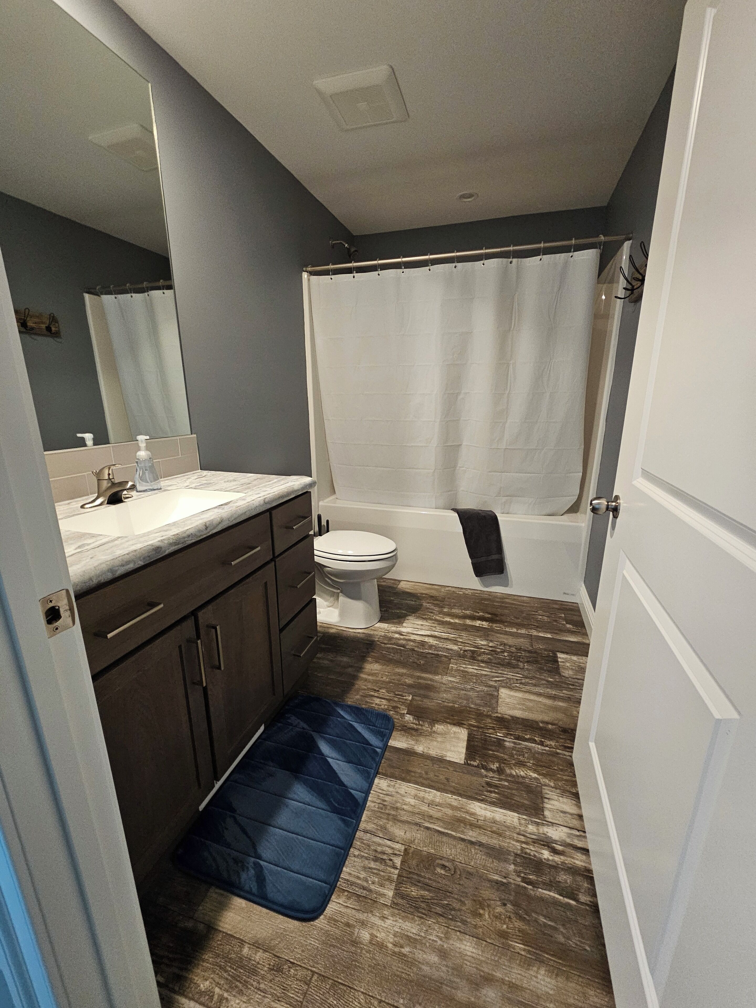 A bathroom with a toilet, sink, mirror, and shower curtain.