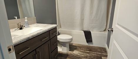A bathroom with a toilet, sink, mirror, and shower curtain.
