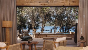 A wooden deck with outdoor seating, a hot tub, and a view of the sea.