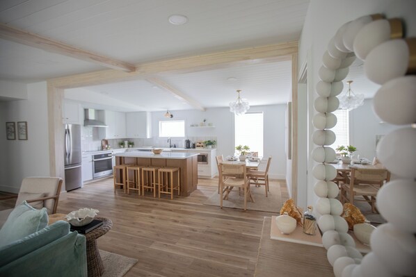 A spacious kitchen with wooden cabinets, a central island with bar stools, and a dining area with a table and chairs.