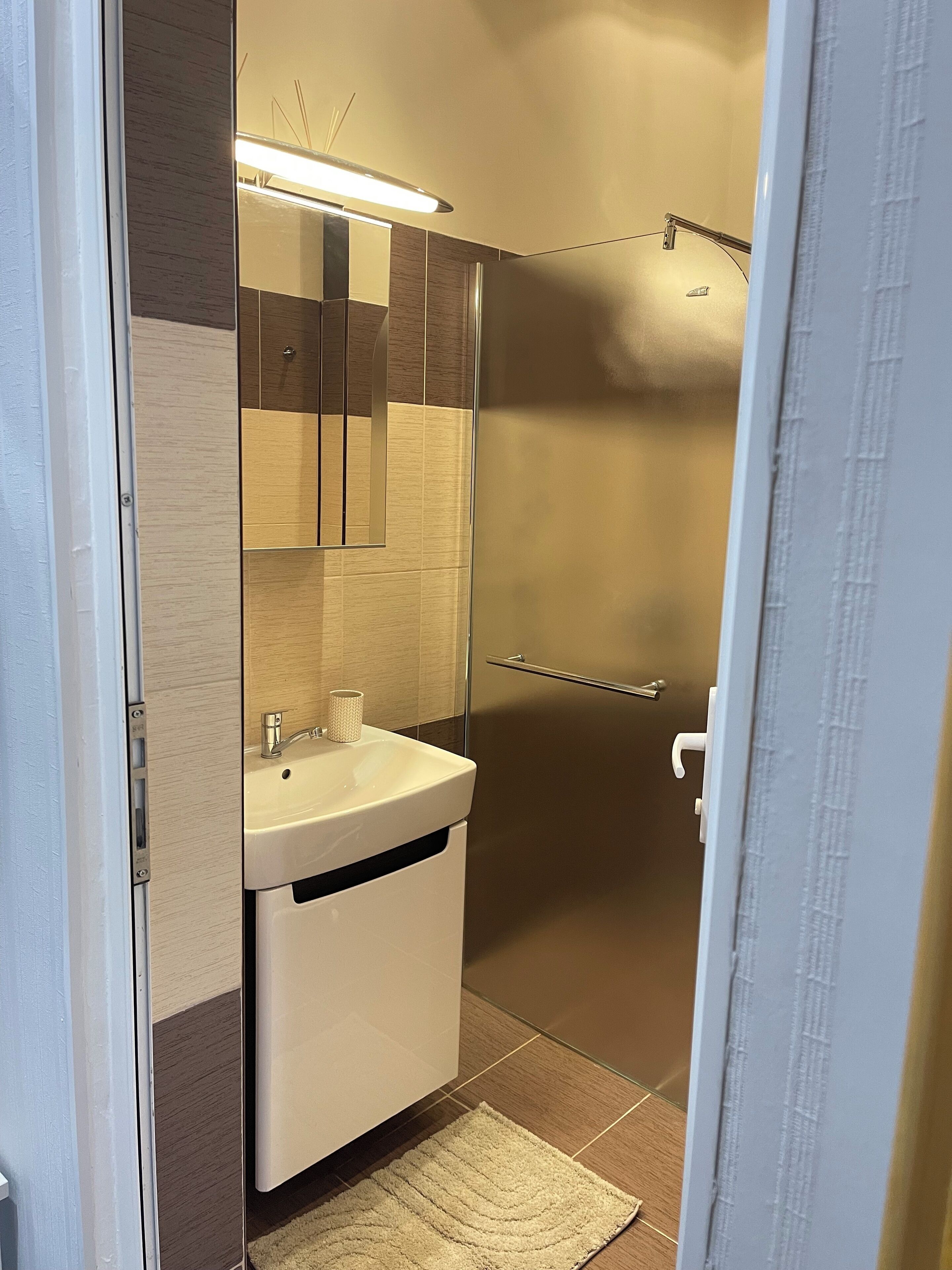A modern bathroom with a sink, mirror, and shower.