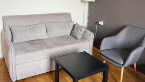 A living room with a grey sofa, a black coffee table, and a grey armchair. - Dara House (Plovdiv)