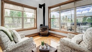 A cozy room with two large windows, a fireplace, and patterned furniture.