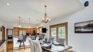 A spacious kitchen with wooden cabinets, a dining area with a large wooden table and chairs, and a chandelier.