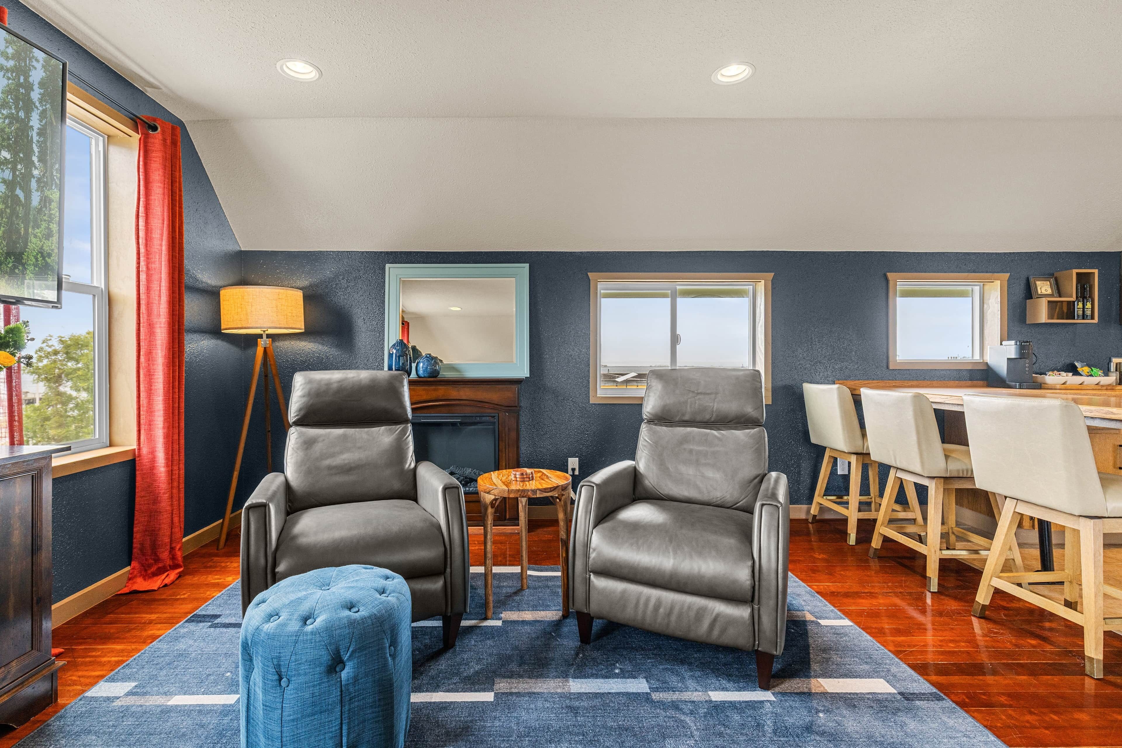 A modern living room with two leather armchairs, a coffee table, and a dining area with a wooden table and chairs.