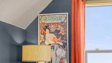 Une pièce avec un canapé, une lampe, un tableau et une fenêtre avec des rideaux.