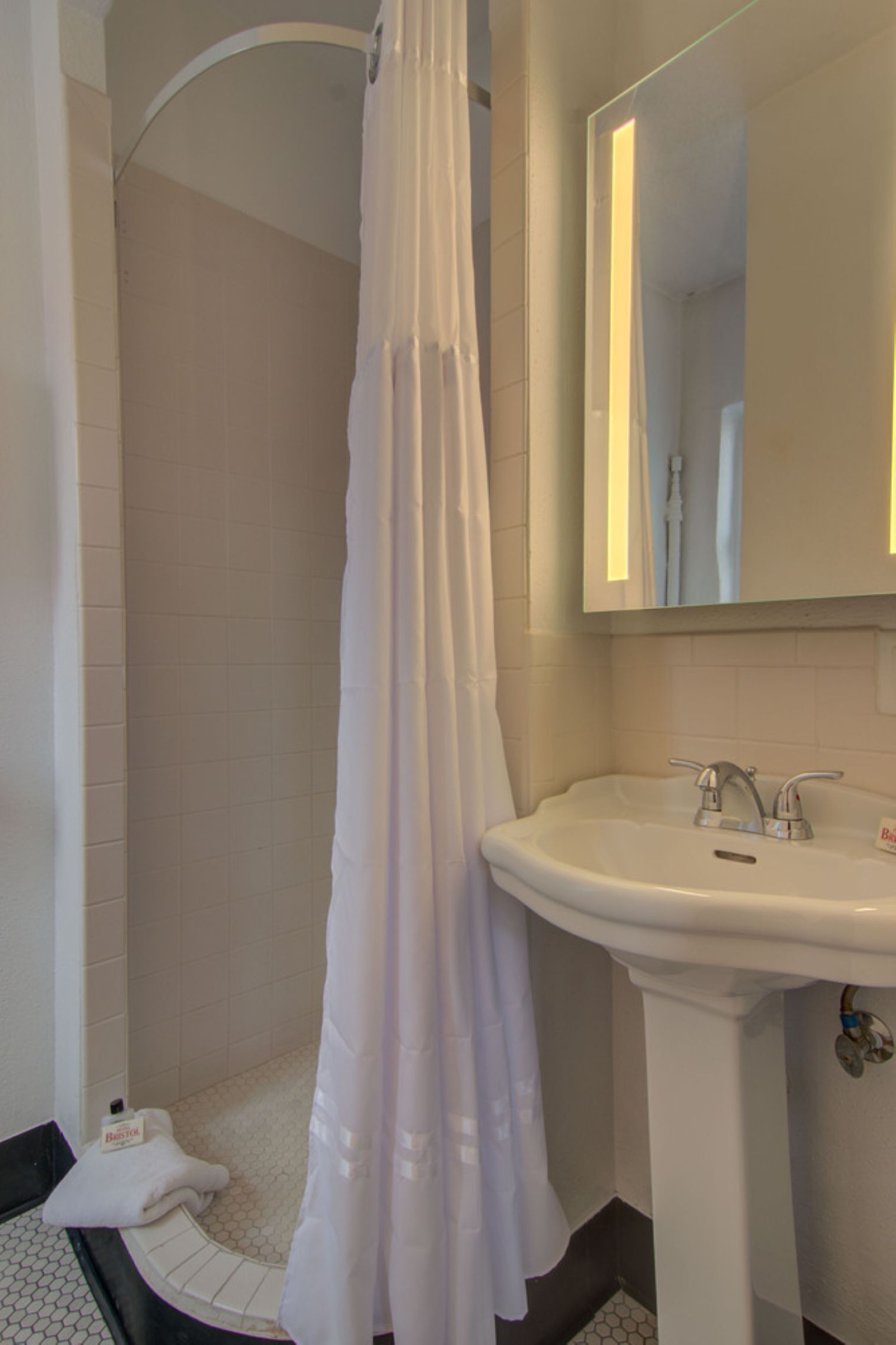 Une salle de bain avec une douche, un lavabo et un miroir.
