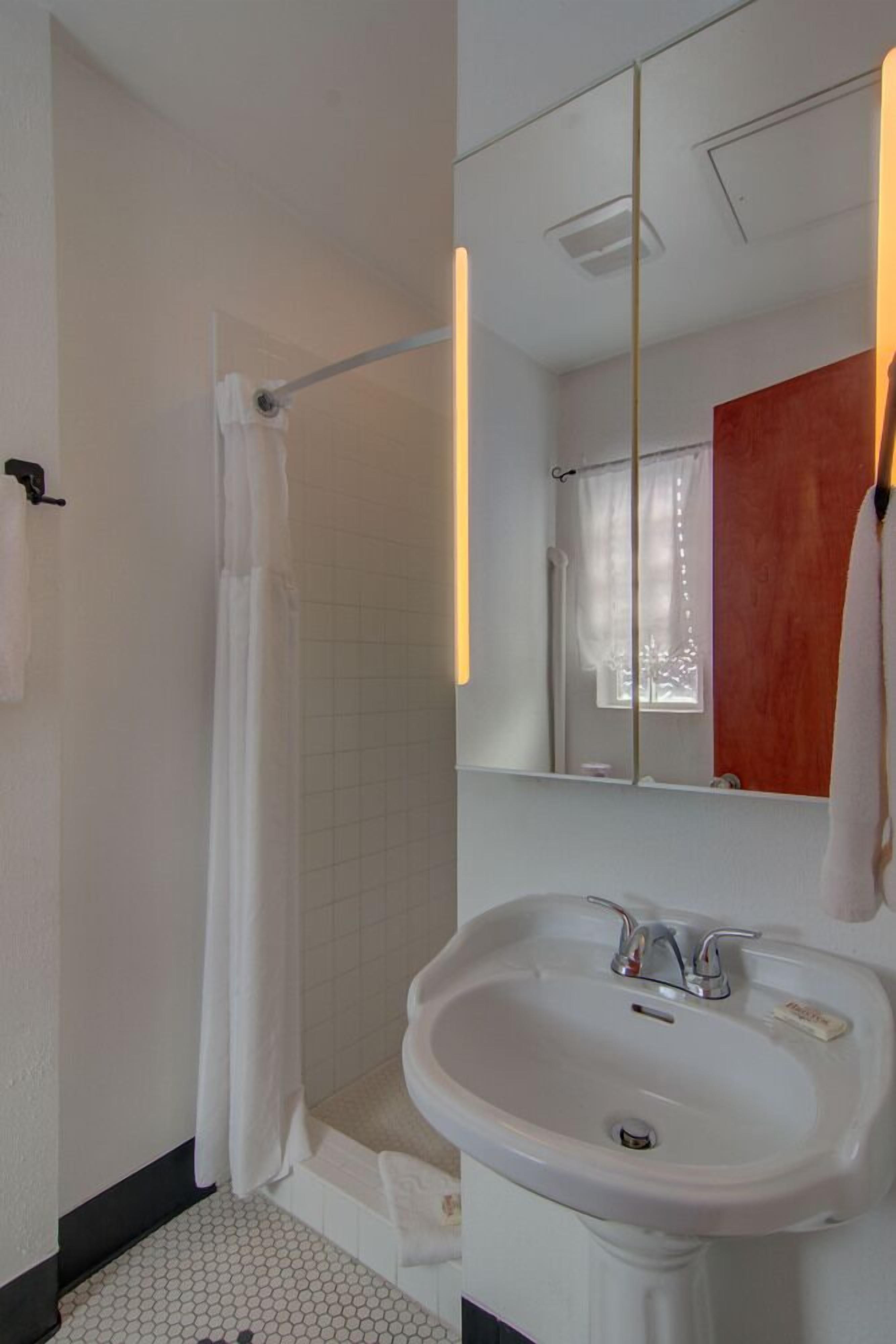 A bathroom with a white sink, a shower curtain, a mirror, and a towel rack.