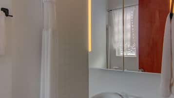 A bathroom with a white sink, a shower curtain, a mirror, and a towel rack.