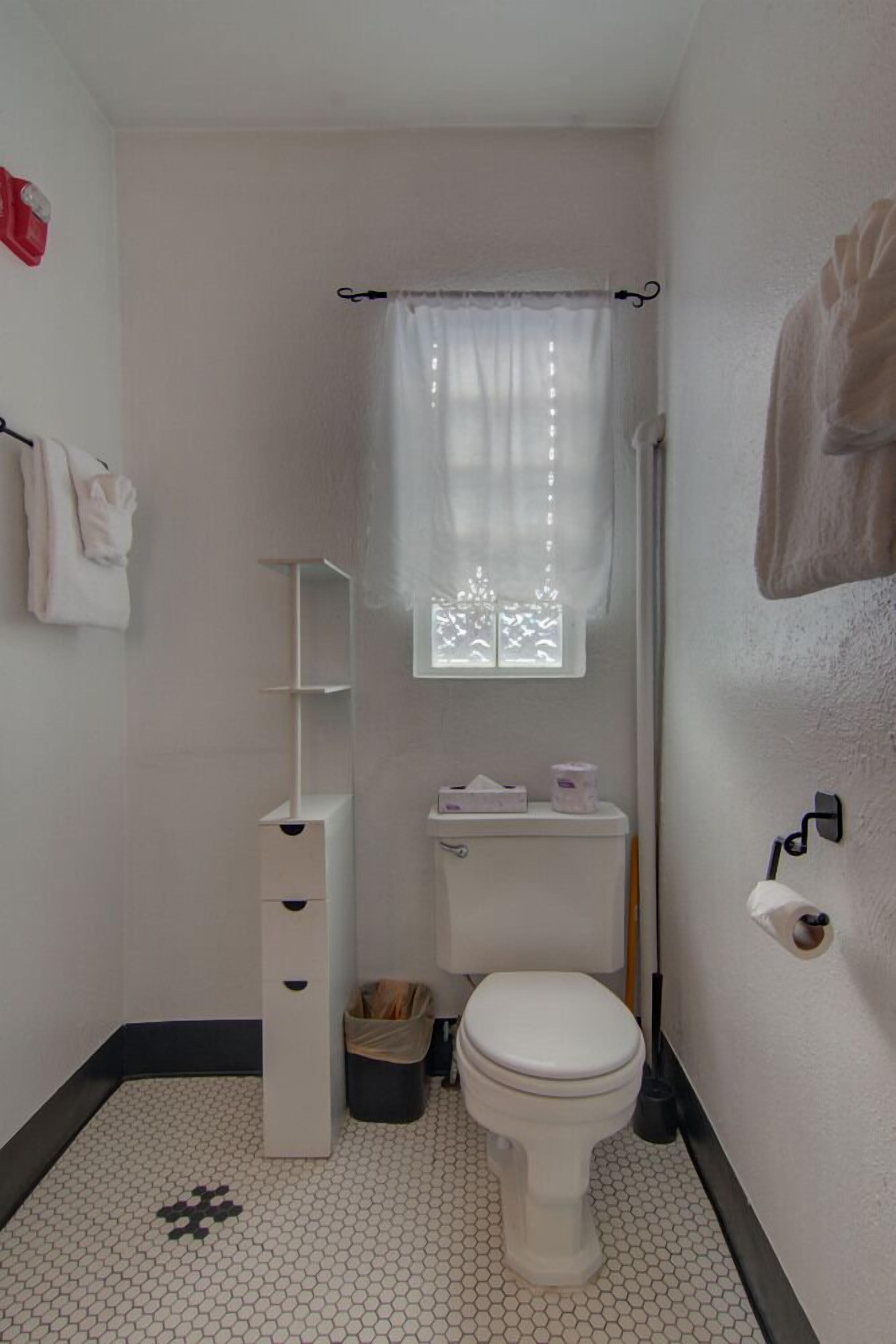 A small, clean bathroom with a toilet, a sink, a shower curtain, and a window.