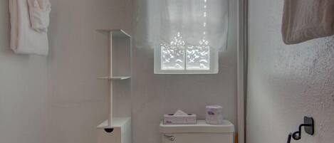A small, clean bathroom with a toilet, a sink, a shower curtain, and a window.