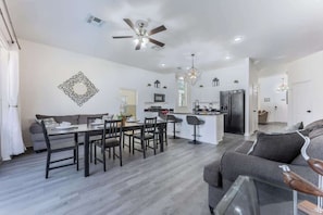 A modern kitchen with a central island, a dining area with a table and chairs, and a living area with a sofa and a coffee table. - Luxury Family Villa w Private Pool 10 min Disney (Davenport)
