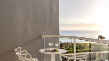A balcony with a white chair, a small round table, and a glass railing.