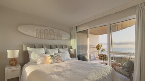 A spacious bedroom with a large bed, a nightstand with a lamp, and a balcony with a view of the sea. - 2 Brm Beachfront Retreat ~ Azure Beachfront Bliss (Palm Beach)