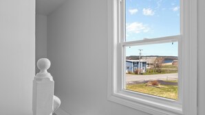 Una escalera con balaustres blancos y vista a un edificio a través de una ventana.
