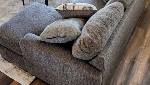 A living room with a grey sectional sofa, a round coffee table, and a potted plant.