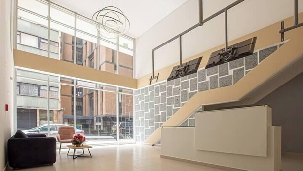 A spacious lobby with a staircase, large windows, and a reception desk.