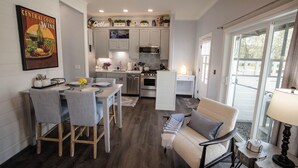 A compact kitchen with a dining area, a sofa, and a large window.