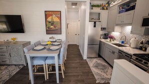 A modern kitchen with a central island, a dining area with striped chairs, and a kitchen island with decorative items.