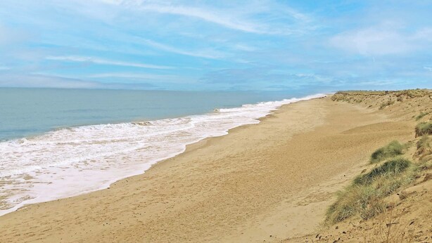 A beach with a clear sky and gentle waves.