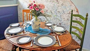 A dining table set with plates, cutlery, and a vase of flowers against a wall with a map.