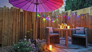A patio with wicker furniture, a table with candles, and a purple umbrella.