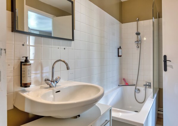 A bathroom with a white sink, a mirror, a shower, and a white bathtub.