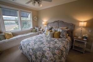 A bedroom with a large bed, a bench by the window, and two bedside tables with lamps.