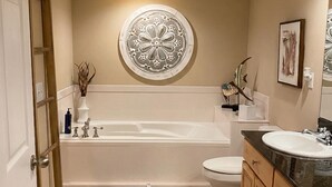 Un baño con bañera, inodoro, tocador y un adorno en la pared.