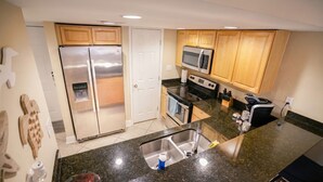 Una cocina moderna con electrodomésticos de acero inoxidable, armarios de madera y encimera de granito.