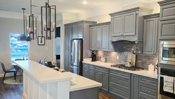 A modern kitchen with a large island, grey cabinetry, stainless steel appliances, and pendant lighting. - Experience the gold standard of Ocean Springs. Private 3BR home with a personal touch you won't find in hotels. Space, style, and local soul. (Ocean Springs)