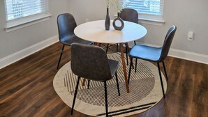 A dining area with a round table, four chairs, a vase with flowers, and a hanging light fixture. - Experience the gold standard of Ocean Springs. Private 3BR home with a personal touch you won't find in hotels. Space, style, and local soul. (Ocean Springs)
