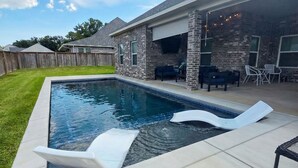 A backyard with a swimming pool, a covered patio area, and a brick house. - Experience the gold standard of Ocean Springs. Private 3BR home with a personal touch you won't find in hotels. Space, style, and local soul. (Ocean Springs)