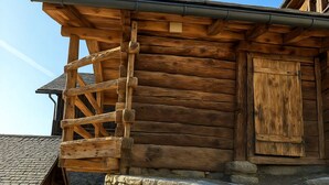 A wooden log cabin with a stone foundation, a wooden staircase, and a closed wooden door. - Les Mayens d'Adrien (Mase)