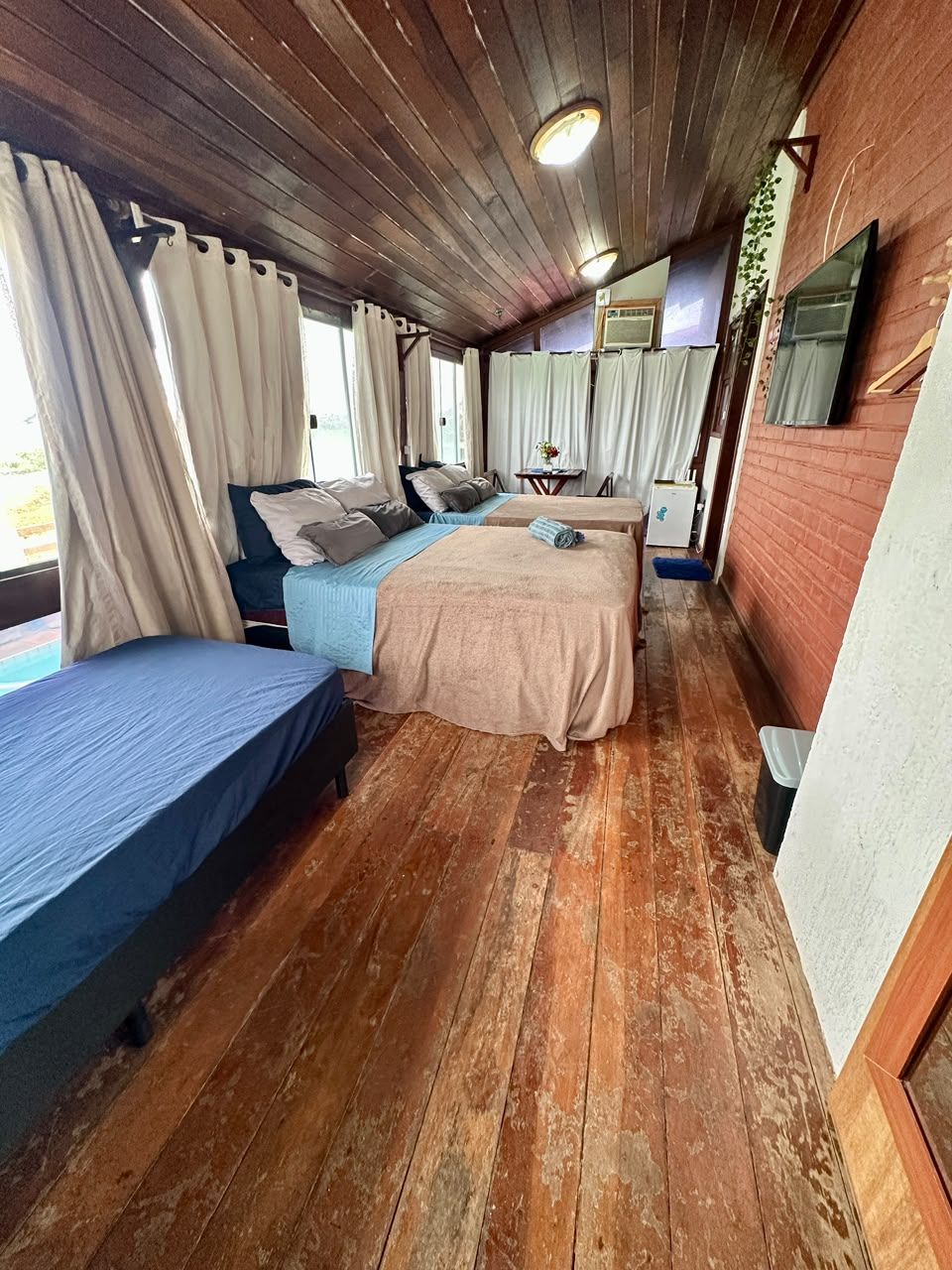 Una habitación con dos camas, suelo de madera y pared de ladrillo.
