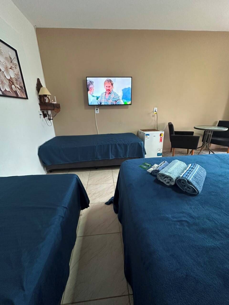A hotel room with two beds, a television, a desk, and a chair.