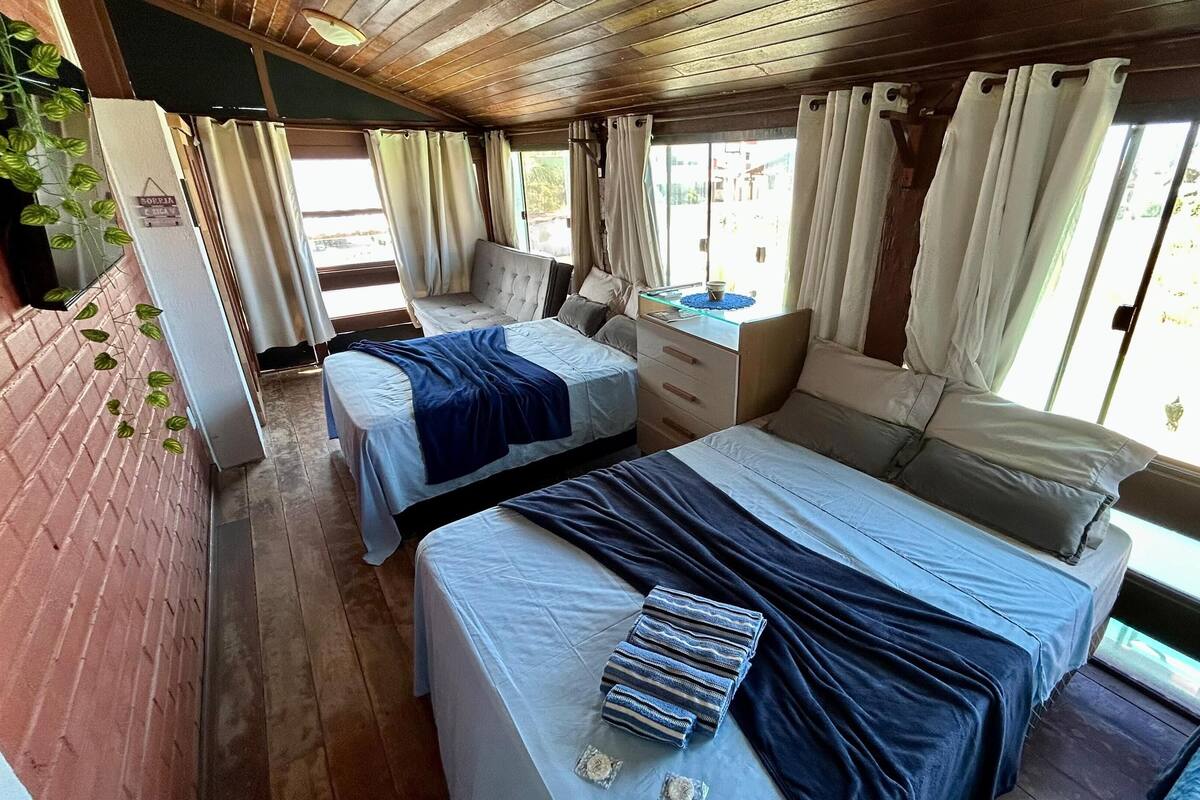 A room with two beds, a wooden ceiling, and a brick wall.