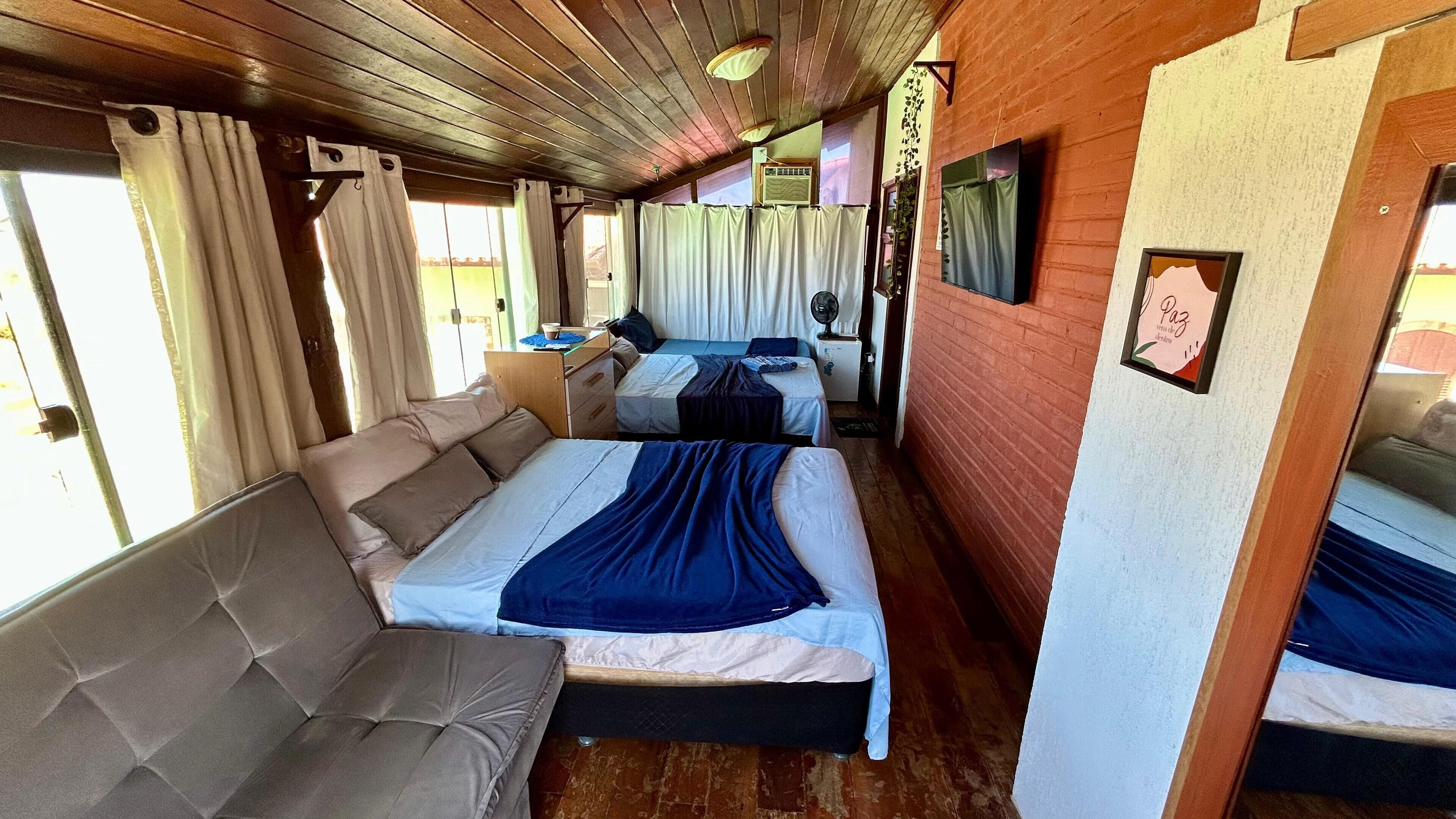 Ein gemütliches Interieur mit einer Couch, zwei Betten, einem kleinen Tisch und einem Fernseher.