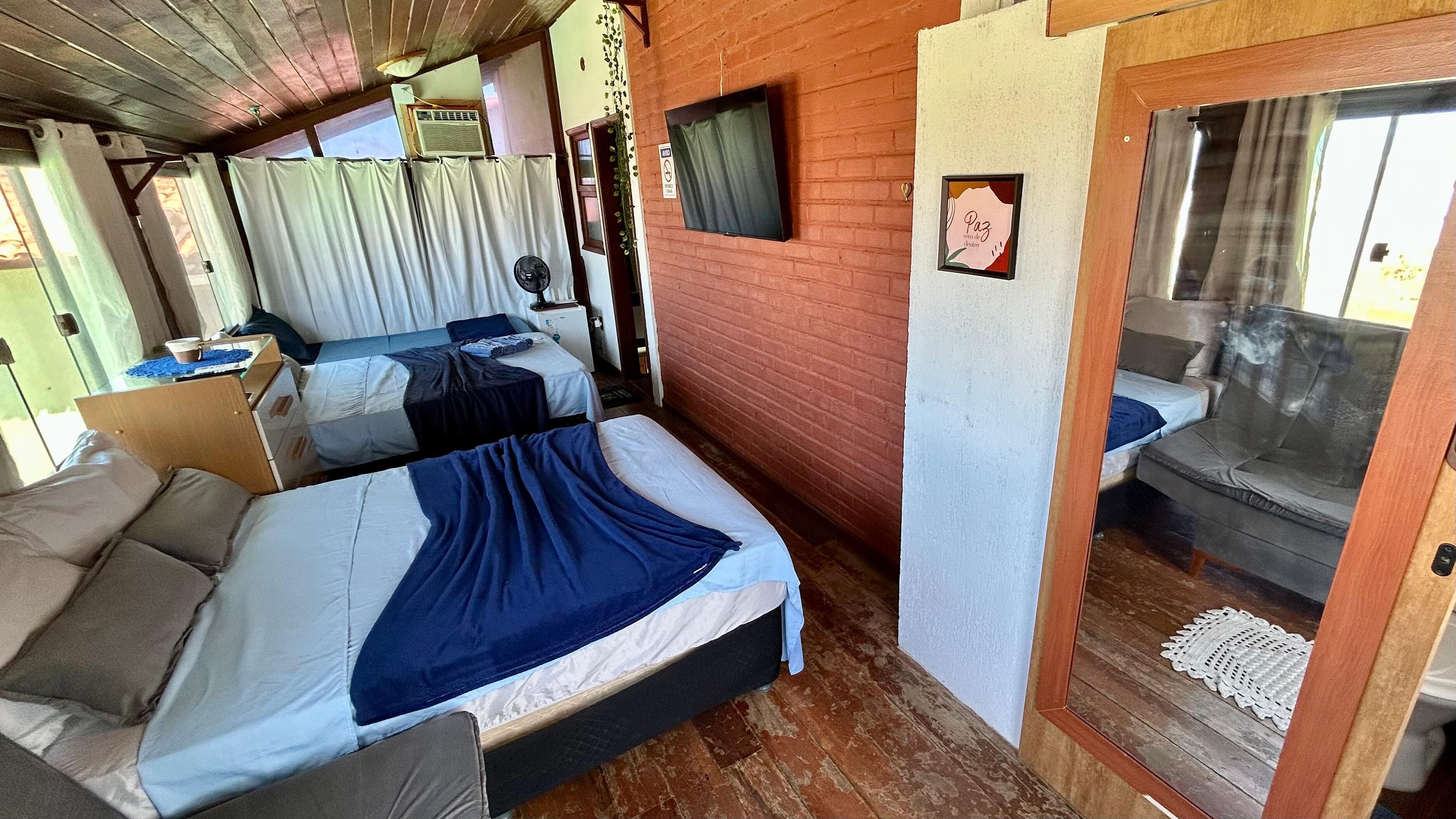 A room with two beds, a television, and a small window.