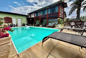 Une piscine avec des chaises longues et un bâtiment doté de grandes fenêtres.
