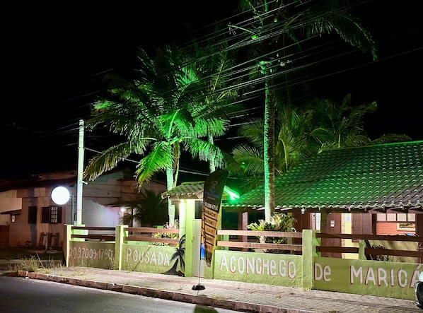 A gated entrance with palm trees and a building with a green roof.
