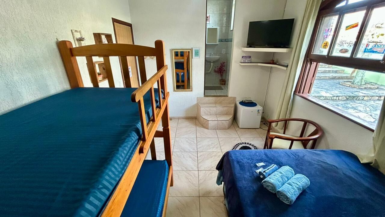 A small room with two wooden beds, a television, a sink, and a window with a view.