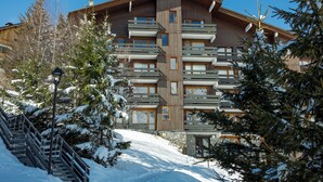 A multi-story wooden building with balconies, surrounded by snow-covered trees.