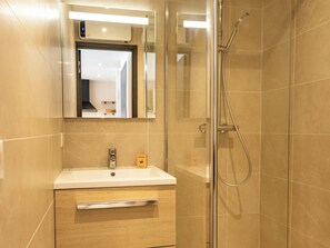 Une salle de bain moderne avec une douche à parois de verre, un lavabo blanc et un meuble-lavabo en bois.