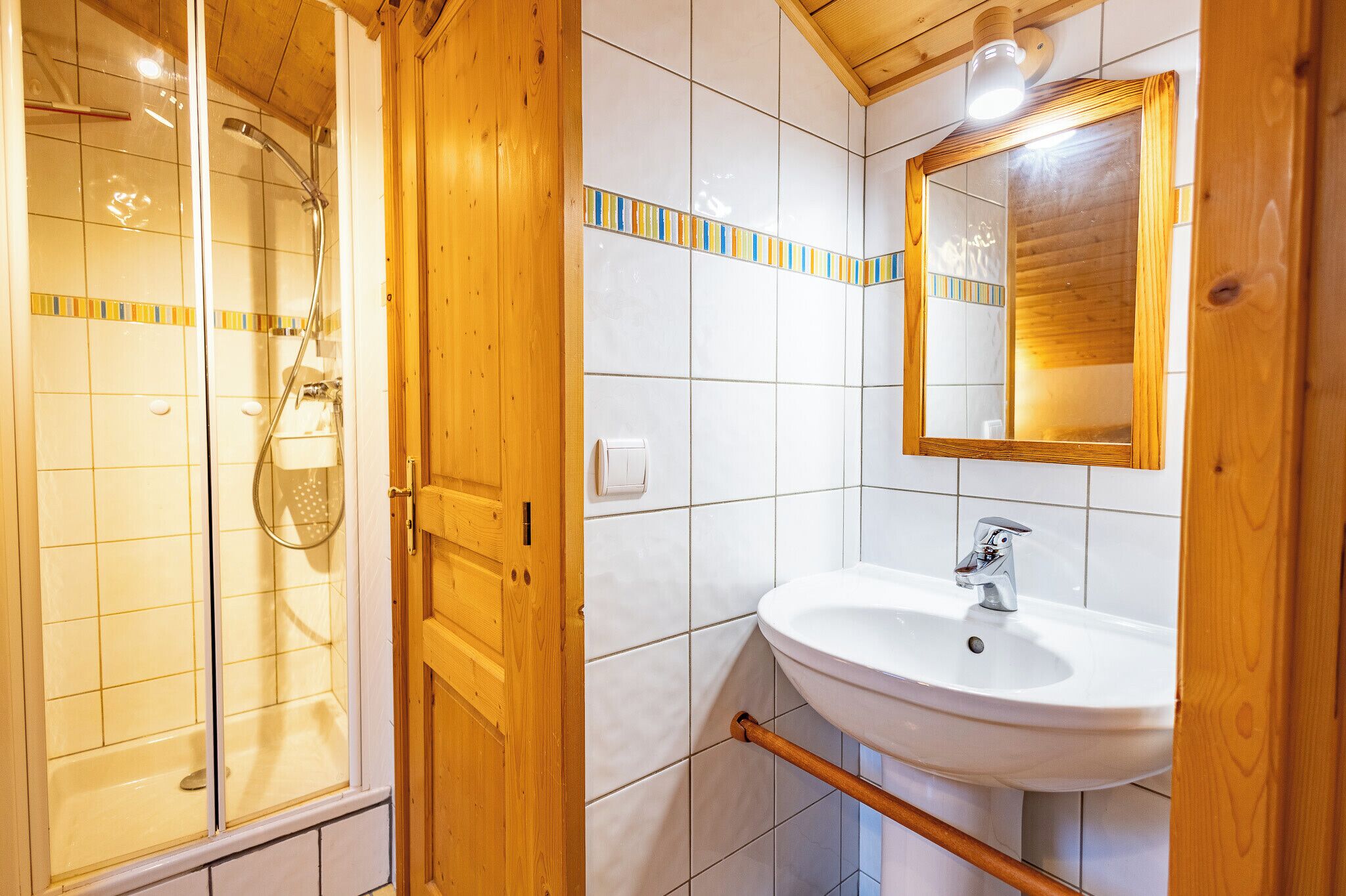 A bathroom with a shower, sink, and wooden paneling.