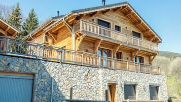 Una cabaña de madera con cimientos de piedra, varios balcones y un garaje.
