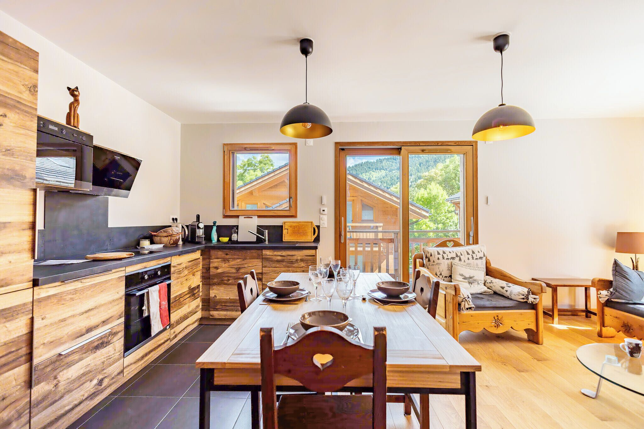 A modern kitchen with wooden cabinets, a dining table set for six, and a cozy seating area with a sofa and armchairs.